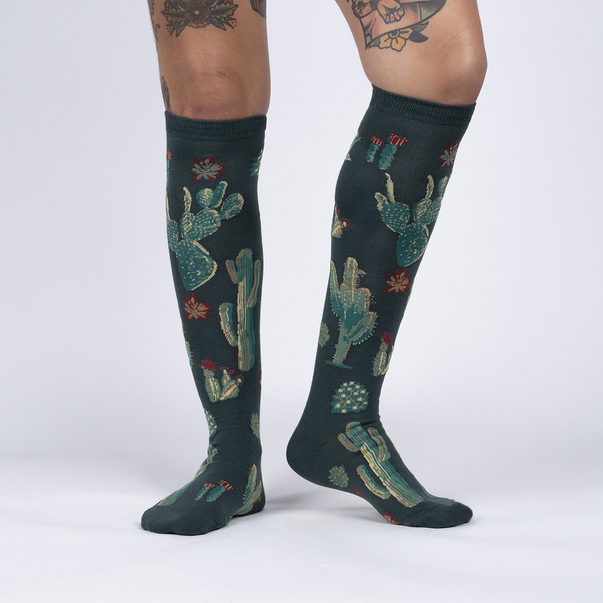 A person wearing green knee high socks with cacti all over, front view - The Sockery