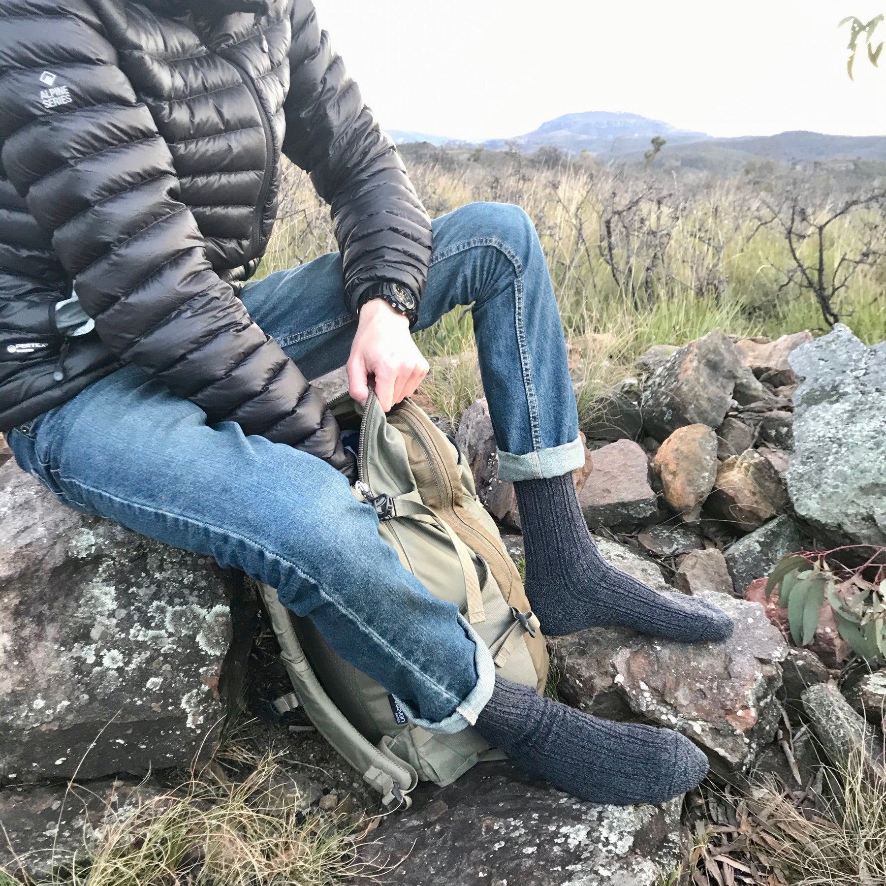 man resting on rocks with a bag wearing Extra Warm Merino Wool Sock in Charcoal - TheSockery