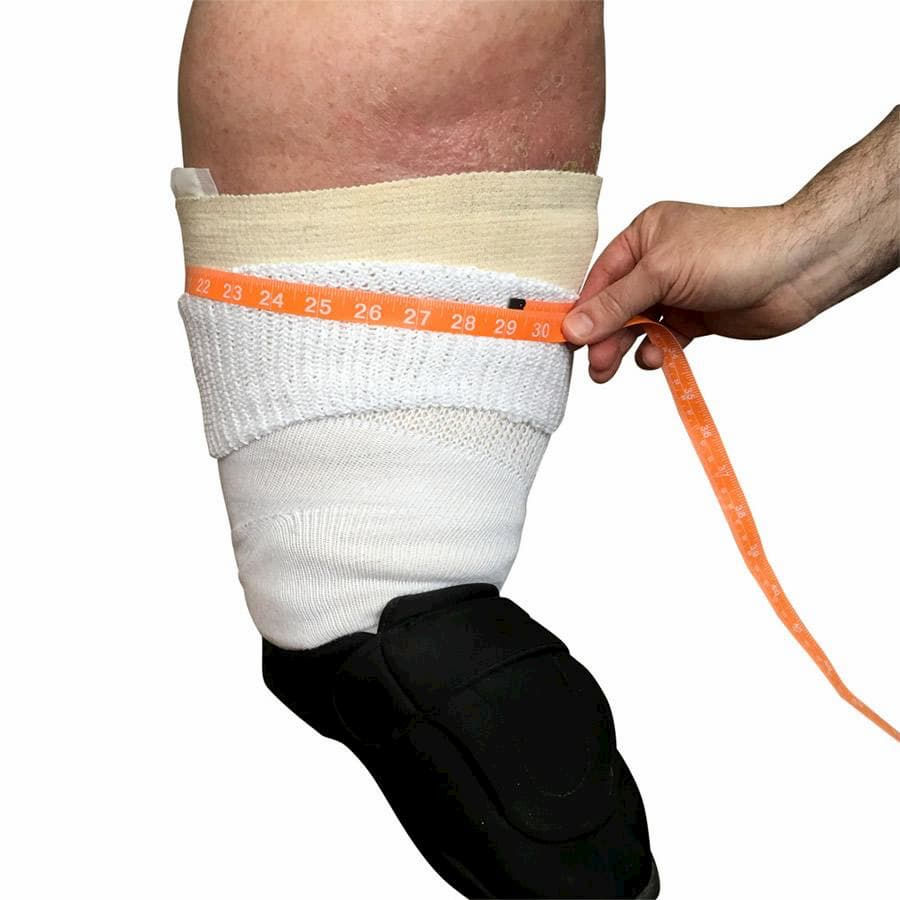 A person with a medical brace wearing a white bariatric sock. Someone is holding a measuring tape around the top of the sock, demonstrating that they comfortably stretch to 29'' (74 cm) - The Sockery