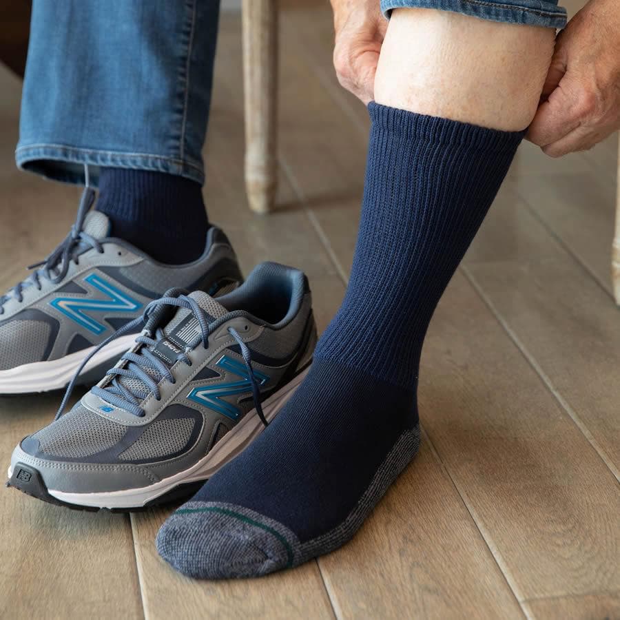 A person putting on a black loose fit crew sock - The Sockery